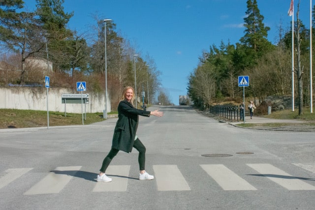 Person som korsar övergångsställe i en stadsmiljö under klar dag.