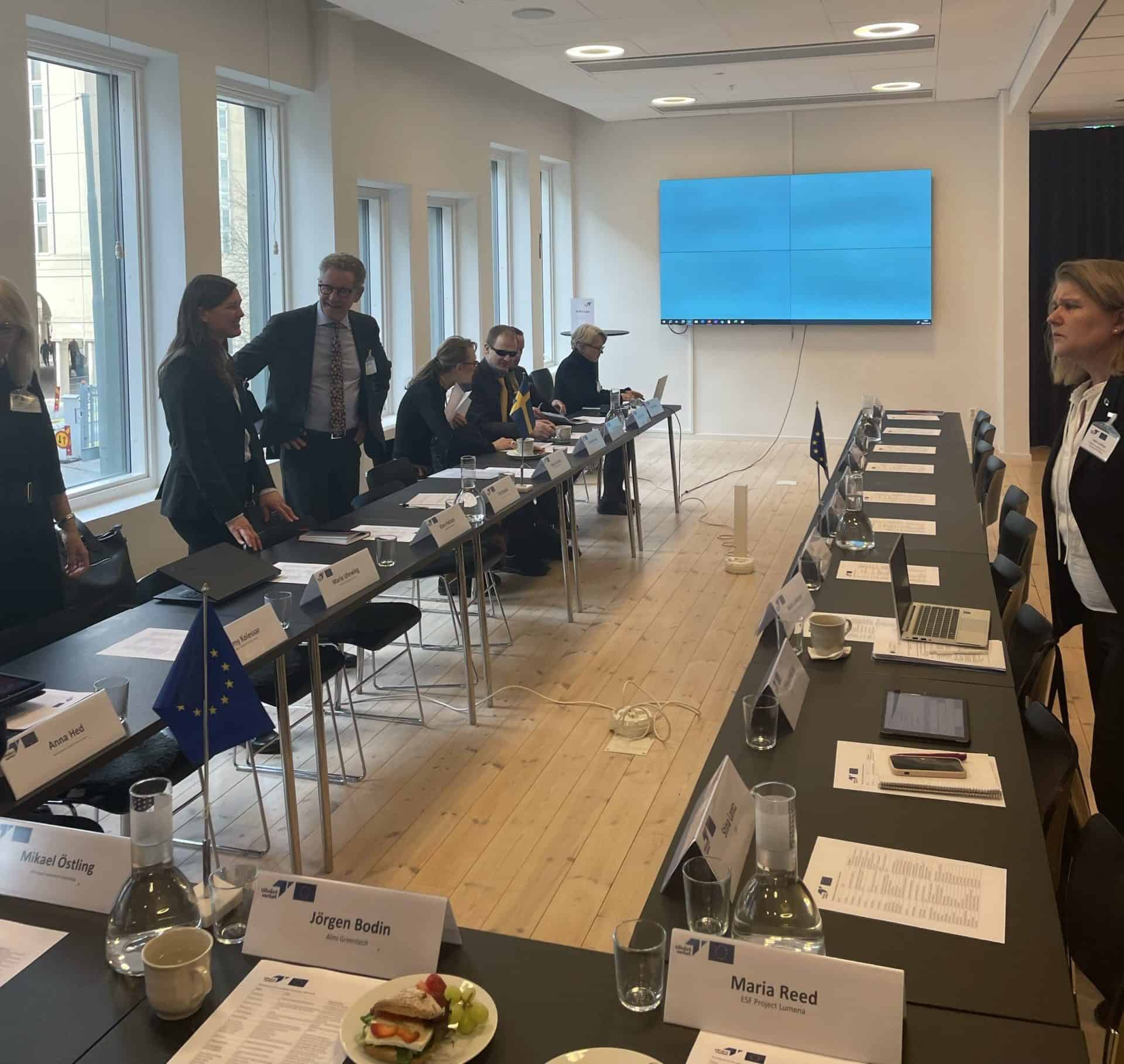 EU-flagga och mötesdeltagare i konferensrum under besök av EU-kommissionen.