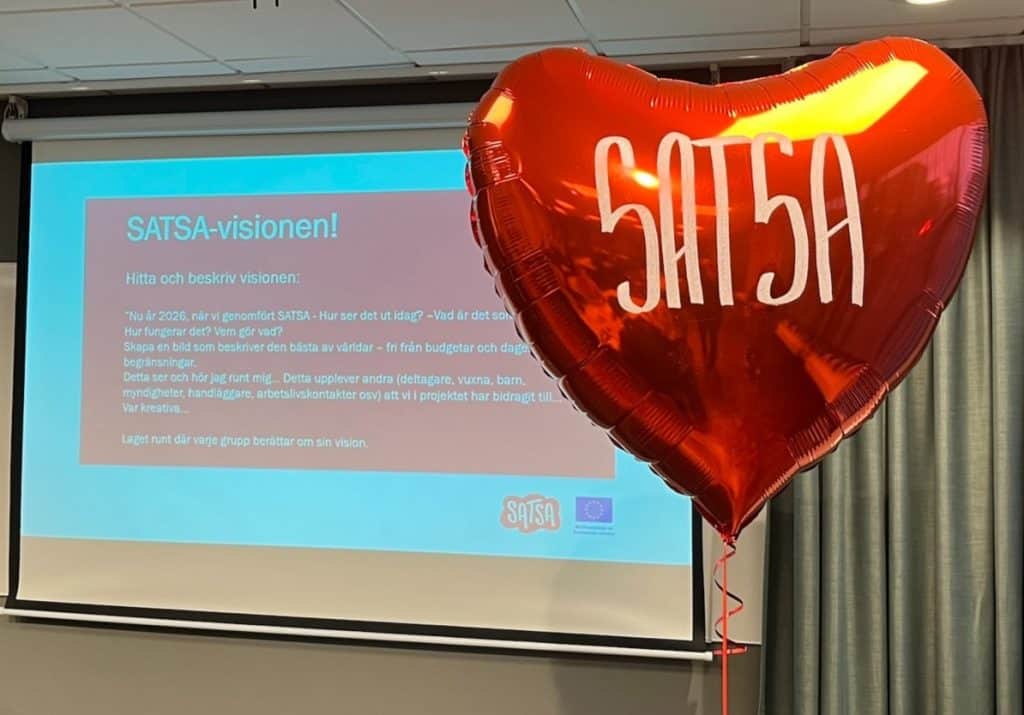 SATSA-logoballong i rött, framför en presentation om SATSA-visionen vid avslutskonferensen.