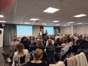 Konferens med presentationer och deltagare i konferensrum.