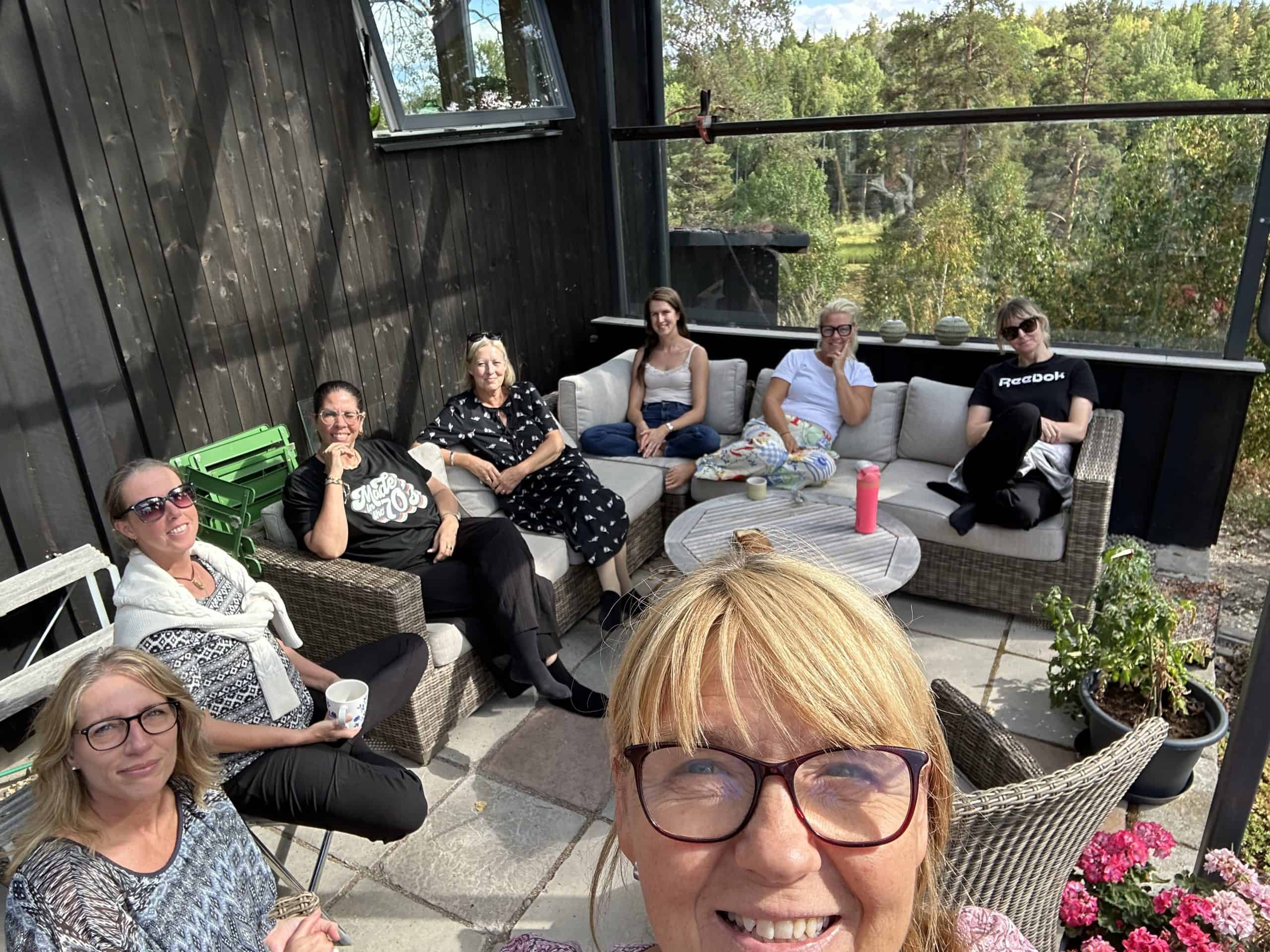 Grupp av personer som sitter på en terrass med utsikt över naturen.